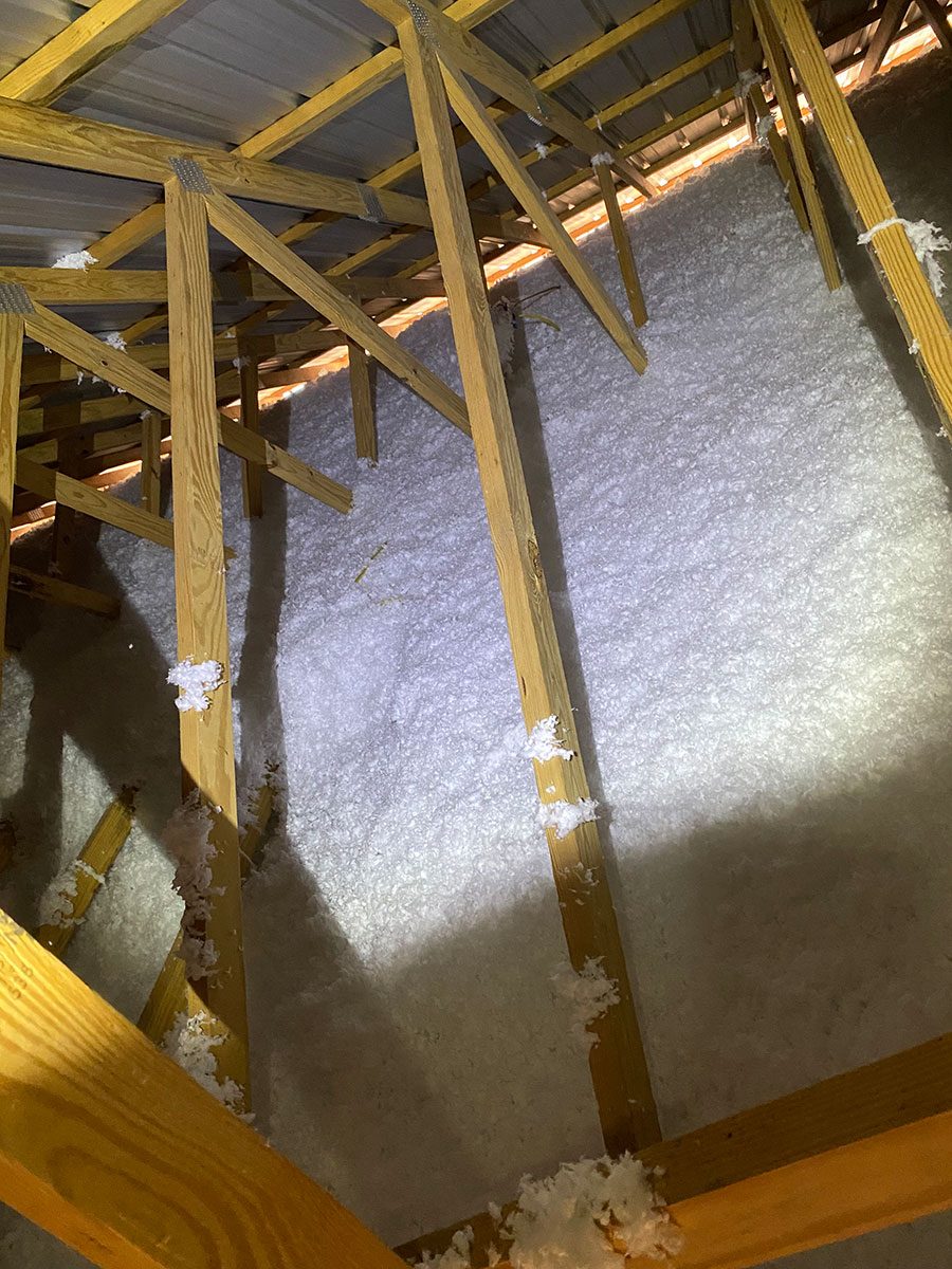 Blown-in fiberglass insulation in attic of metal building